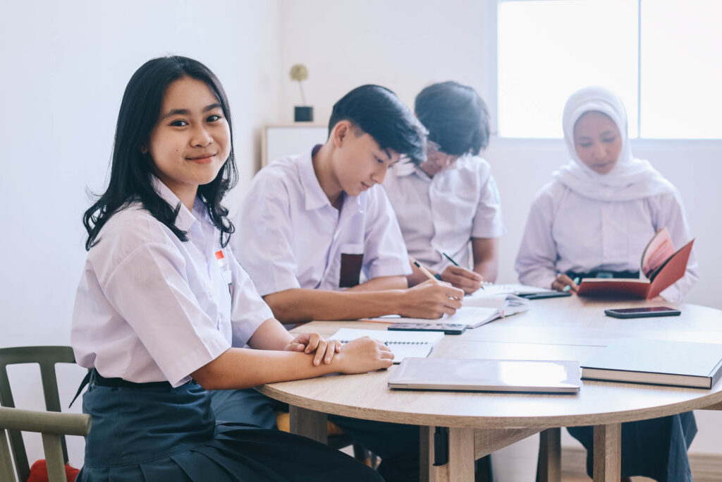 pretty asian schoolgirl sitting smiling lesson classroom